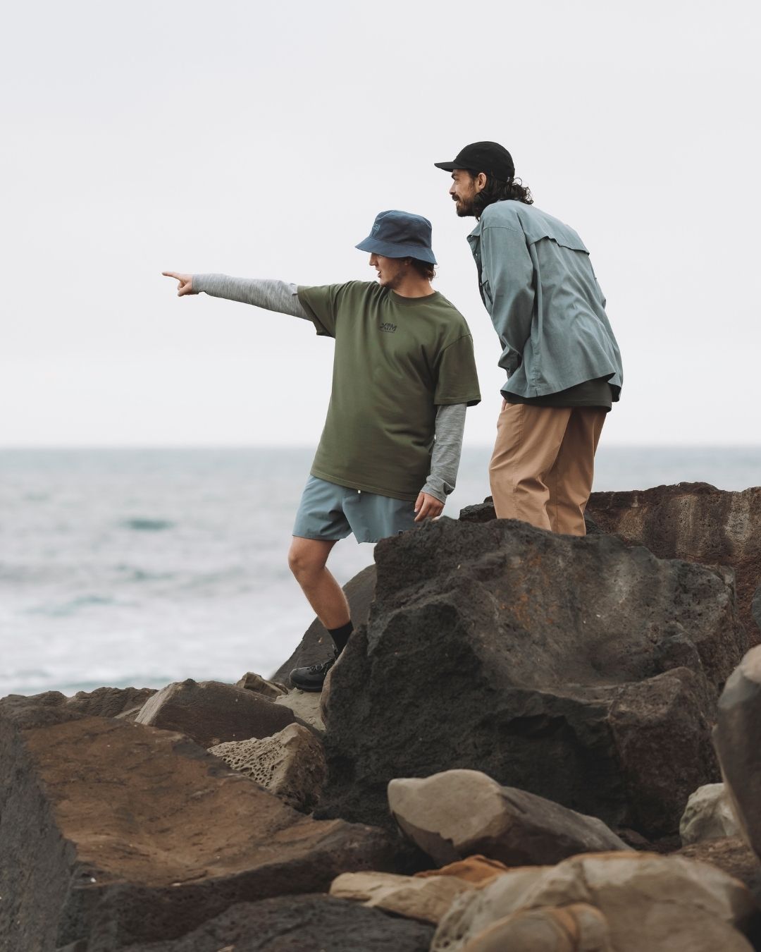 Man in the Indigo XTM Sundew bucket hat pointing out to sea from coastal rocks
