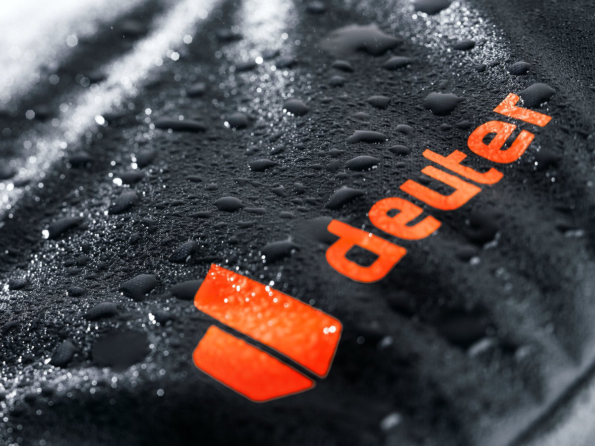 Wet orange Deuter logo on the Jaypack Pro 34+14, water drops on the coated fabric, wider crop