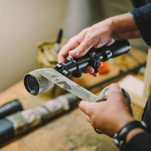 Hands wrapping a scope tube in Camo Form on a workbench