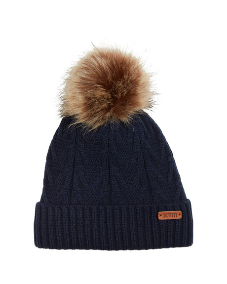 Navy XTM Kids Isla Knit Beanie in dark blue cable knit with brown faux fur pom pom and leather badge