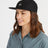 Woman wearing the black XTM Hakea organic cotton cap, three-quarter view