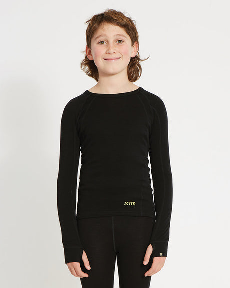 XTM Kids Alpine230 Merino Long Sleeve Thermal Top in Black, front view on a boy showing the crew neck and thumb loops