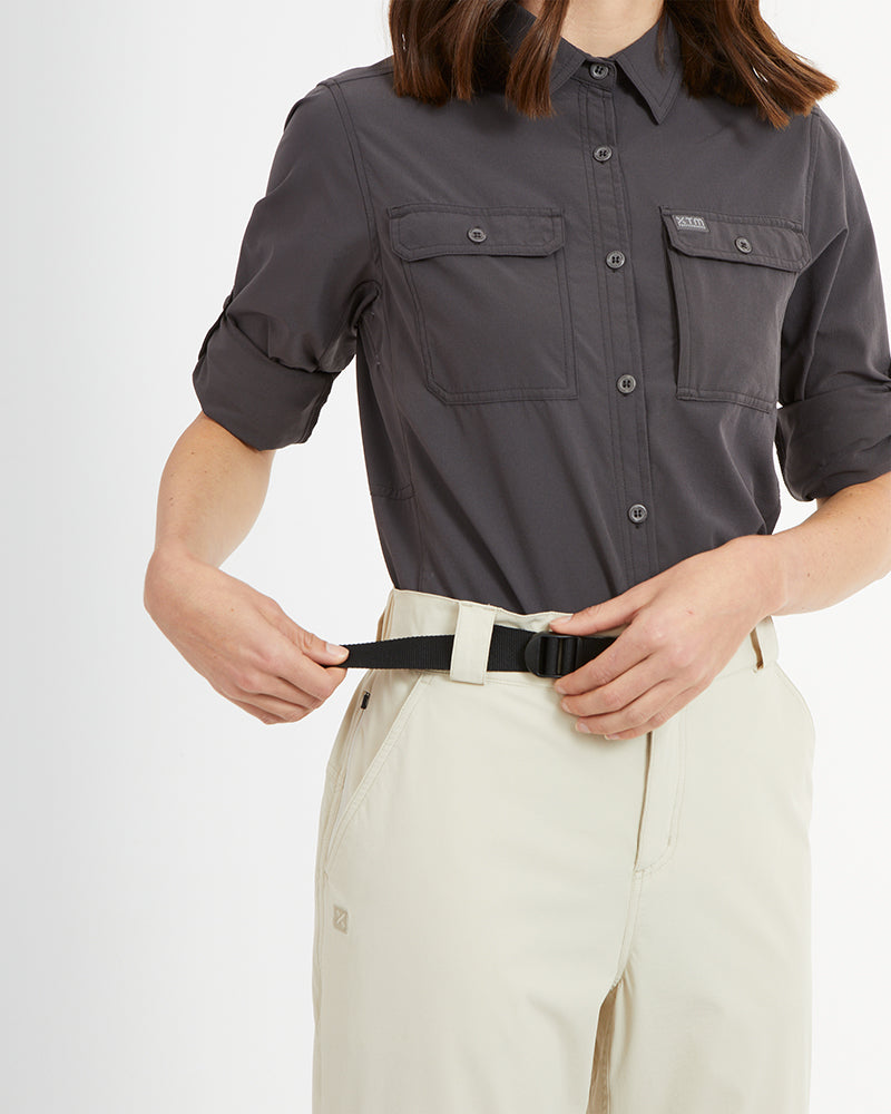 Woman fastening the slide buckle belt on XTM Wye River hiking pants in Sand
