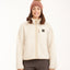 Woman wearing XTM Banksia sherpa fleece jacket in Bone cream, front view zipped up with chest badge