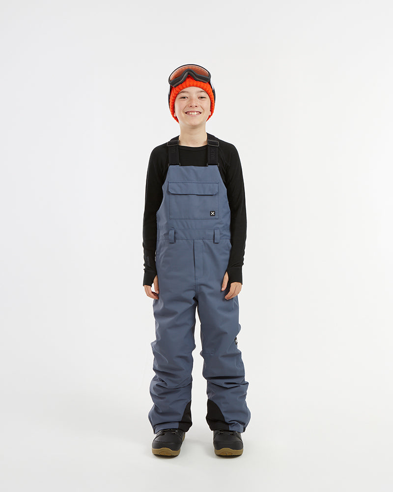XTM Kids Bailey Ski Pant in Indigo Solid, front view on a child showing the chest panel