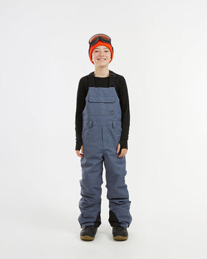 XTM Kids Bailey Ski Pant in Indigo Solid, front view on a child showing the chest panel