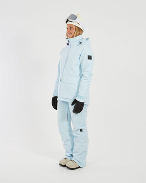 Side view of a woman in the Sky Blue XTM Elevation II jacket showing the sleeve badge