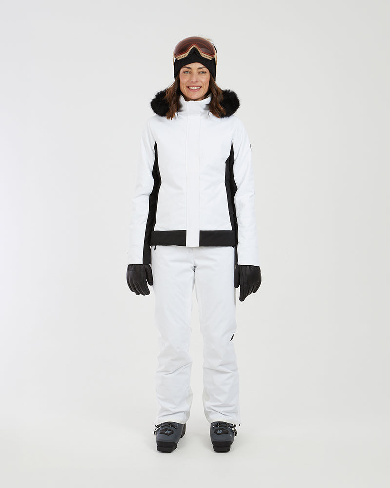 Full-length front view of the white XTM Solace jacket worn with white ski pants and boots