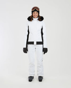 Full-length front view of the white XTM Solace jacket worn with white ski pants and boots