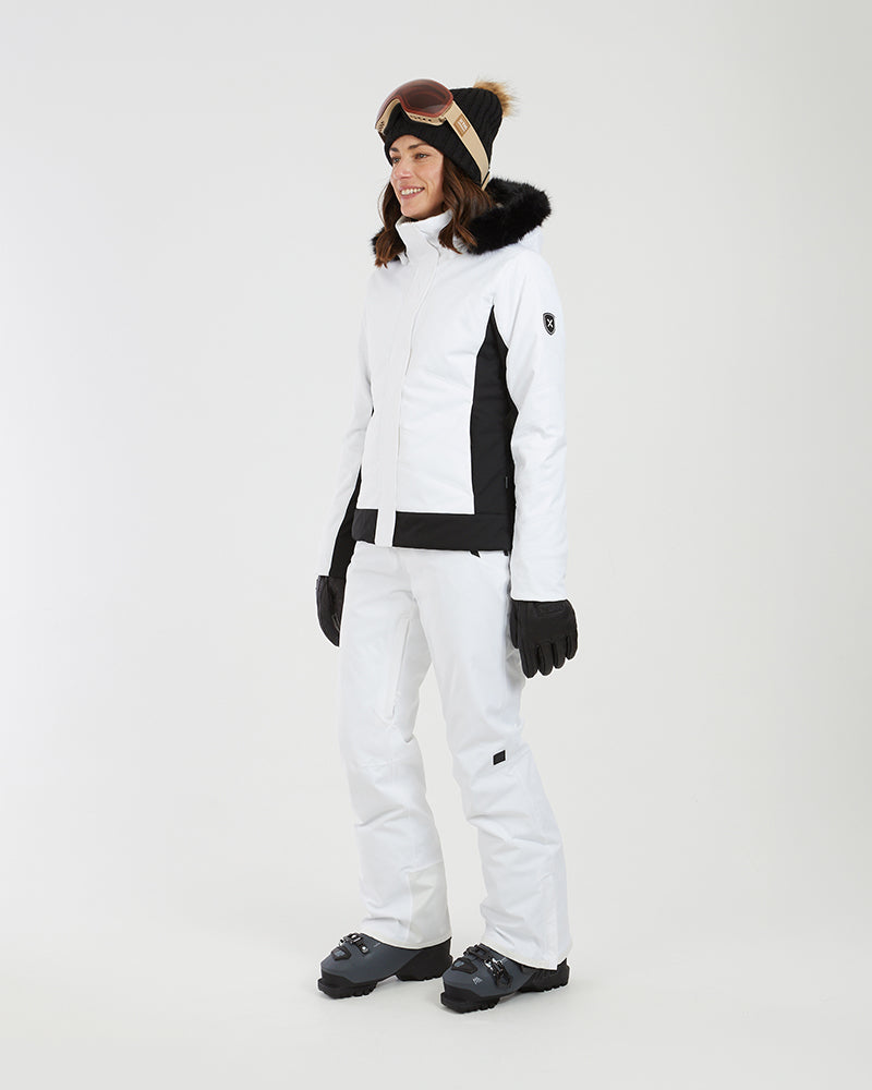 Three-quarter full-length view of a woman in the white XTM Solace ski jacket