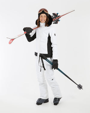 Woman carrying skis and poles in the white XTM Solace women's ski jacket