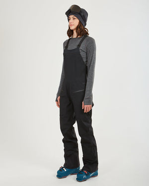 Three-quarter view of the black XTM Stellar 2.0 ski bib pant with ski boots