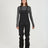 Woman wearing the black XTM Stellar 2.0 hardshell bib pant with ski boots, front view