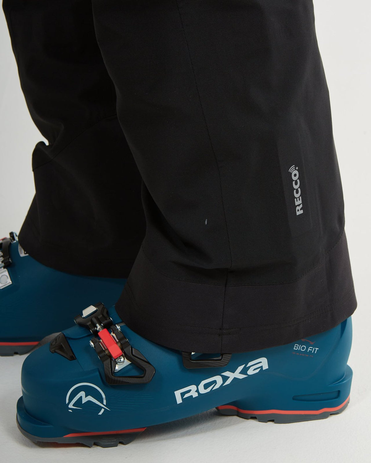 Close-up of the RECCO marking at the cuff of the black XTM Stellar 2.0 pant