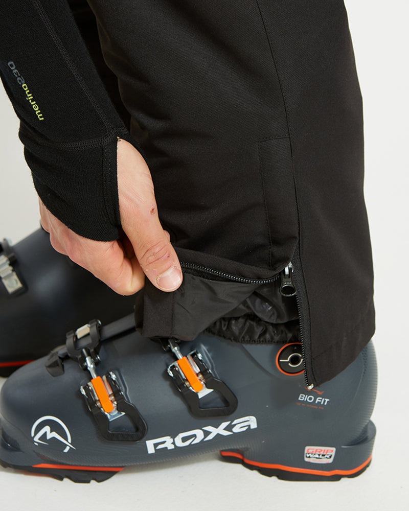 Black XTM Glide ski pant cuff lifted to show the boot gaiter over a ski boot