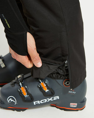 Black XTM Glide ski pant cuff lifted to show the boot gaiter over a ski boot