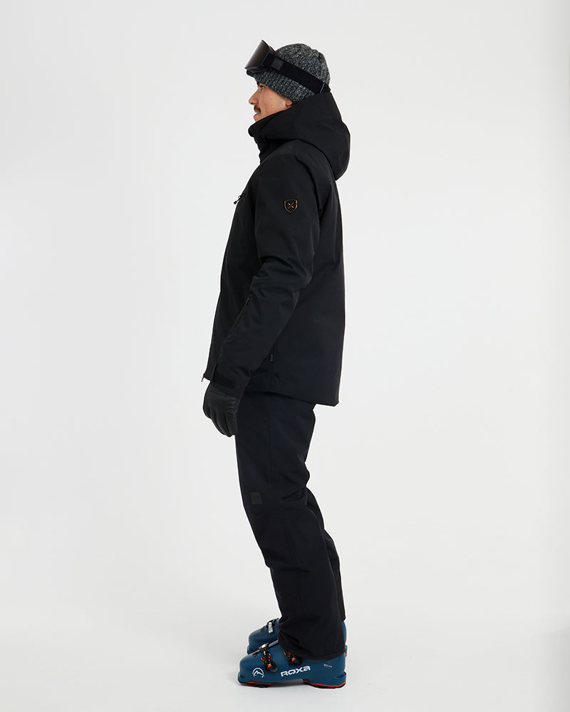Side profile of the Black XTM Quantum snow jacket showing the hood and sleeve pocket
