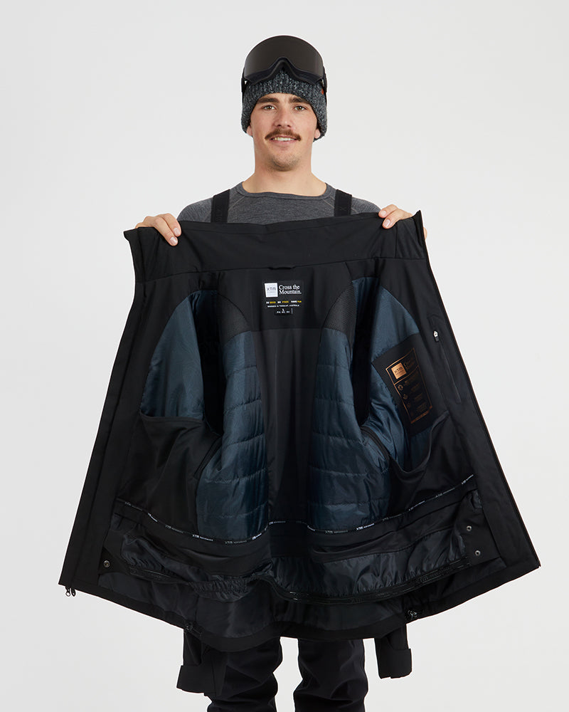 Black XTM Quantum jacket held open to show the quilted insulated lining and powder skirt