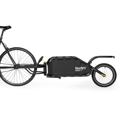 Burley Coho XC hitched behind a black bike, side view showing the single rear wheel and cargo frame