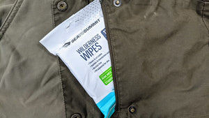 Wilderness Wipes packet tucked into the chest pocket of an olive jacket
