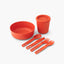 Passage Dinnerware Set in Spicy Orange laid out: bowl, lidded cup and four utensils